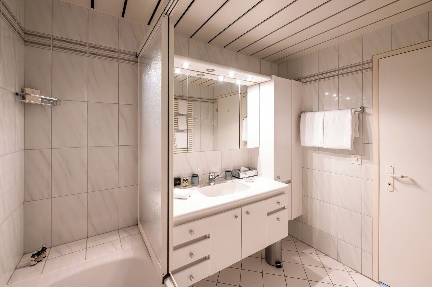 A modern bathroom with a large mirror, a sink, and a shower.