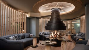 A modern interior with a central fireplace, sofas, and round tables.