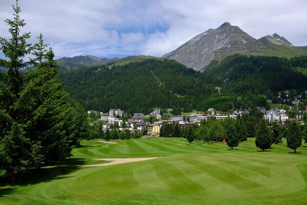 A golf course with a view of a mountainous landscape and a town in the background. - Hotel Seehof Davos (Davos)