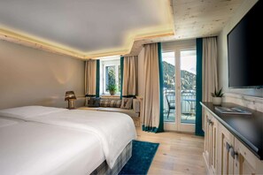A hotel room with a large bed, a desk with a chair, a TV, and a balcony with a view of the mountains. - Hotel Seehof Davos (Davos)