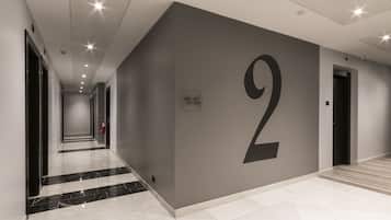A modern hallway with a large number '2' on the wall, a fire extinguisher, and a sign with room numbers.