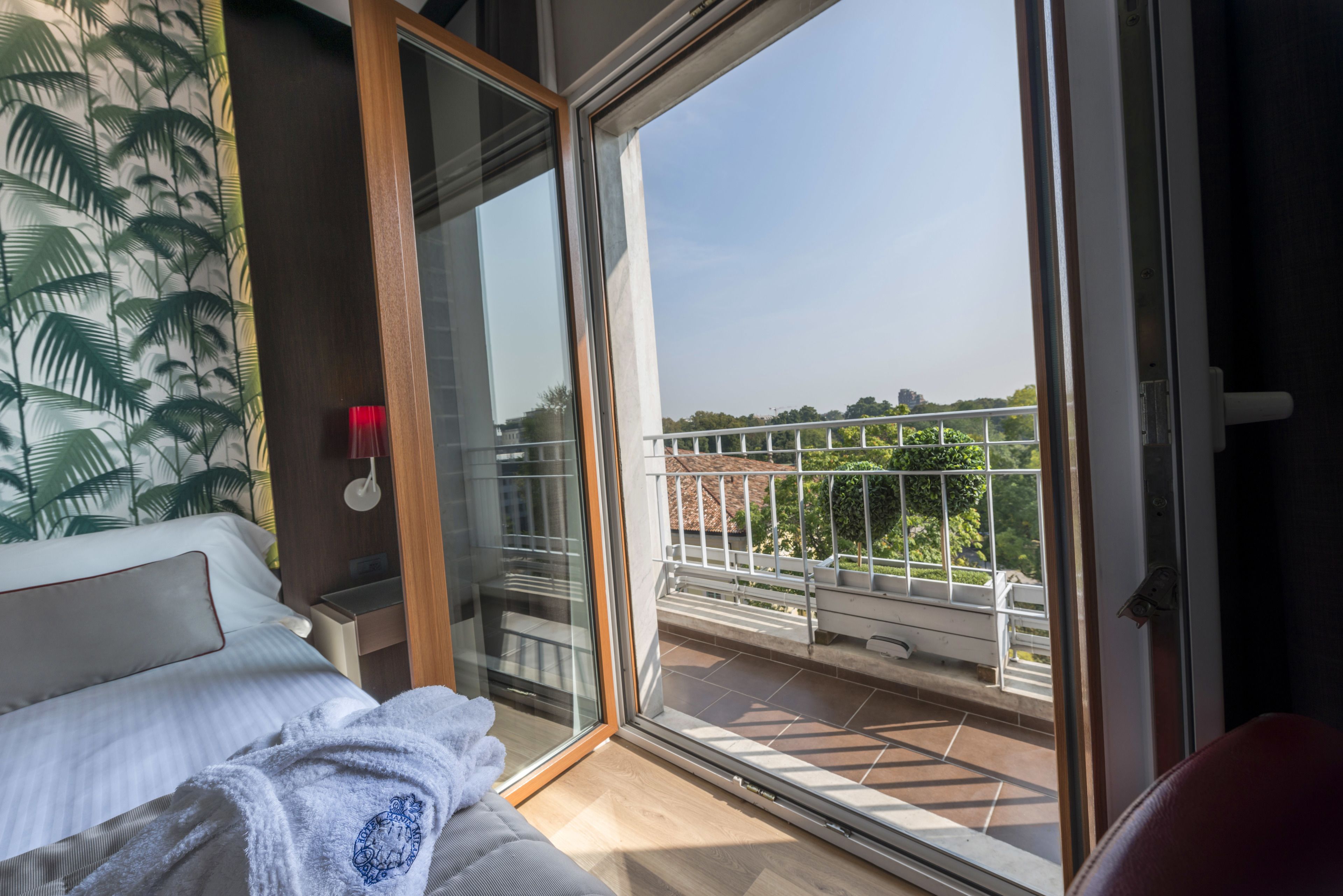 A bedroom with a large sliding glass door leading to a balcony with a view of the city.