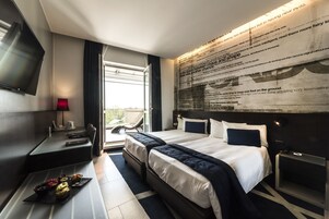 Una habitación de hotel moderna con una cama grande, un escritorio y un televisor de pantalla plana.