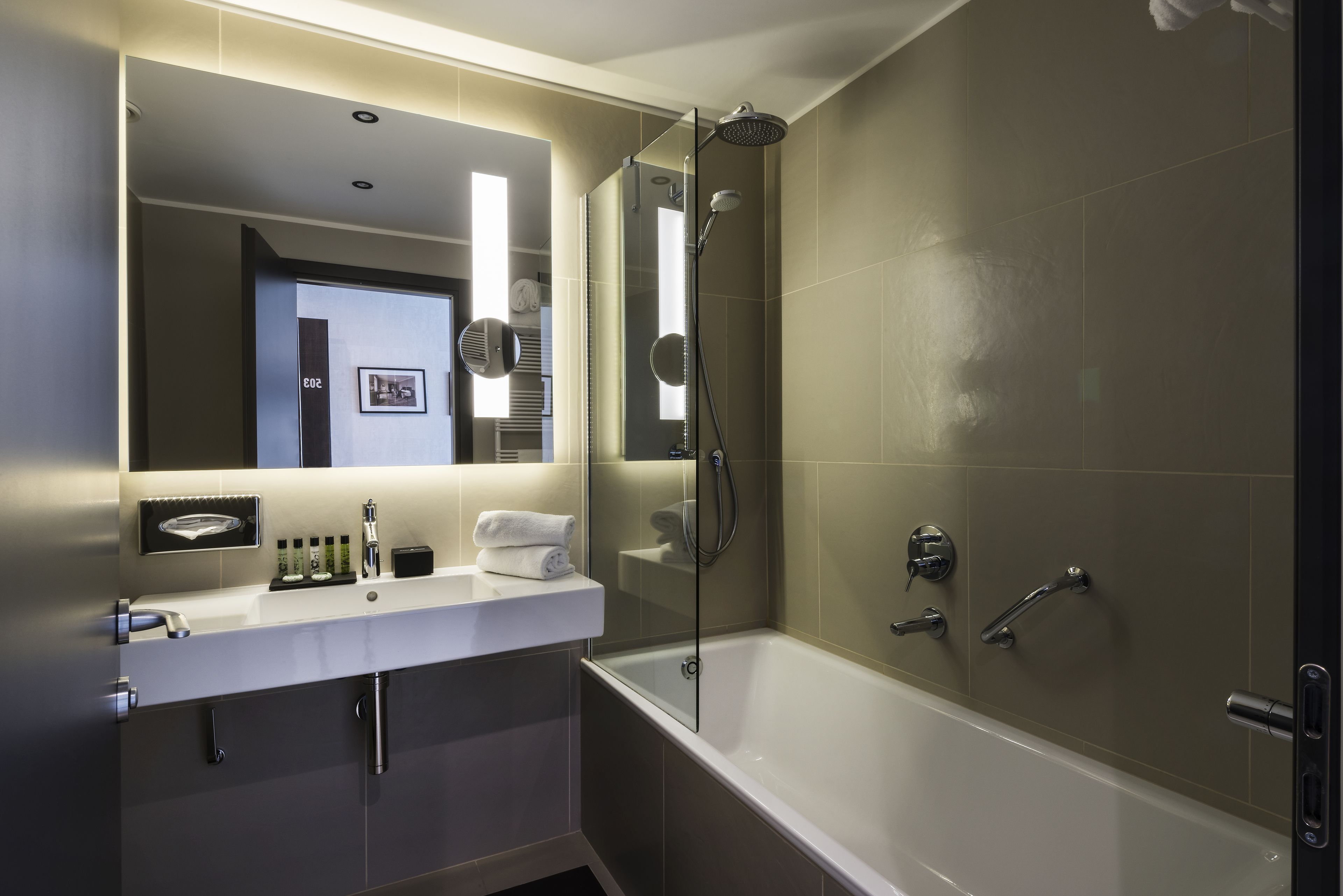 Un baño moderno con ducha envuelta en vidrio, un lavamanos blanco con espejo y una bañera.