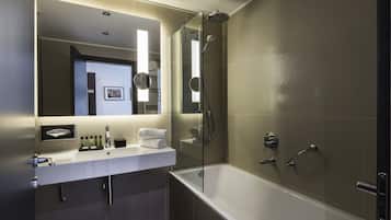 Un baño moderno con ducha envuelta en vidrio, un lavamanos blanco con espejo y una bañera.