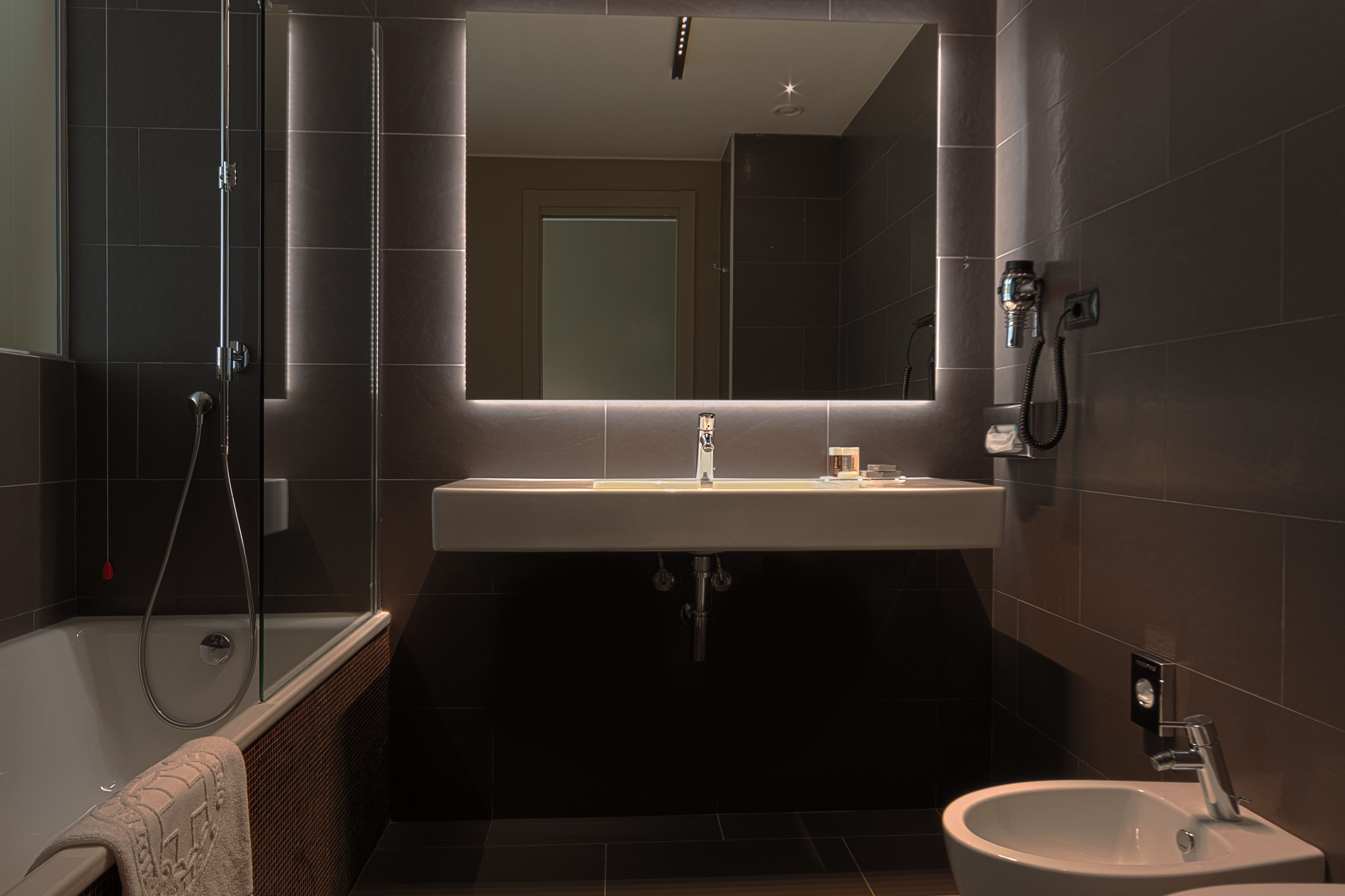 Un bagno moderno con doccia vetrata, uno specchio grande e un lavabo con bidet.