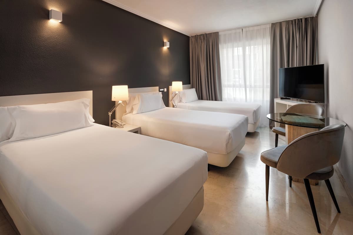 A hotel room with two beds, a TV, a desk, and a chair.