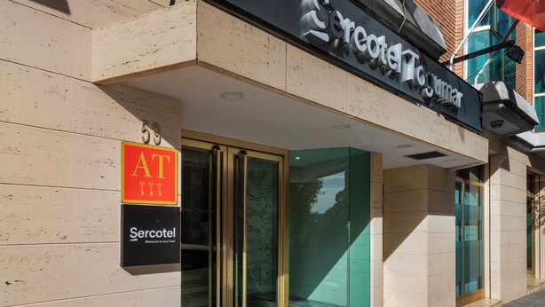 A hotel entrance with a glass door, a sign indicating AT 59, and a welcome sign for Sercotel. - Sercotel Togumar (Madrid)