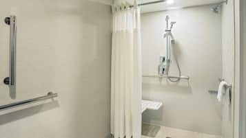 Un baño moderno con ducha, barras de apoyo y un perchero para toallas.