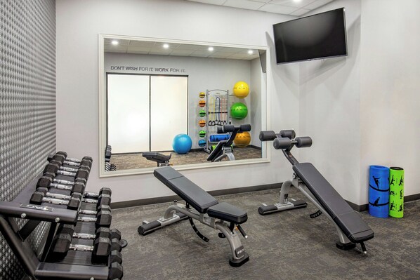 A gym with benches, dumbbells, exercise balls, and a mirror.