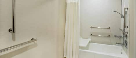 A modern bathroom with a shower, a grab bar, and a white bathtub.
