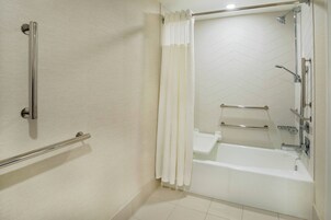 Ein modernes Badezimmer mit Dusche, einer Haltestange und einer weißen Badewanne.