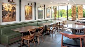 Un restaurante con asientos tapizados en verde, mesas y sillas de madera.