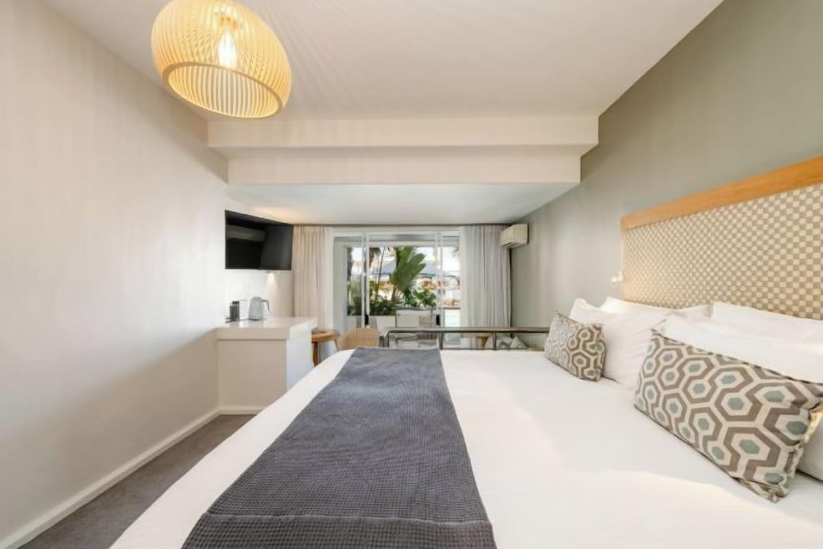 Une chambre d’hôtel avec un grand lit, une table de chevet, un téléviseur à écran plat et une vue sur l’extérieur.