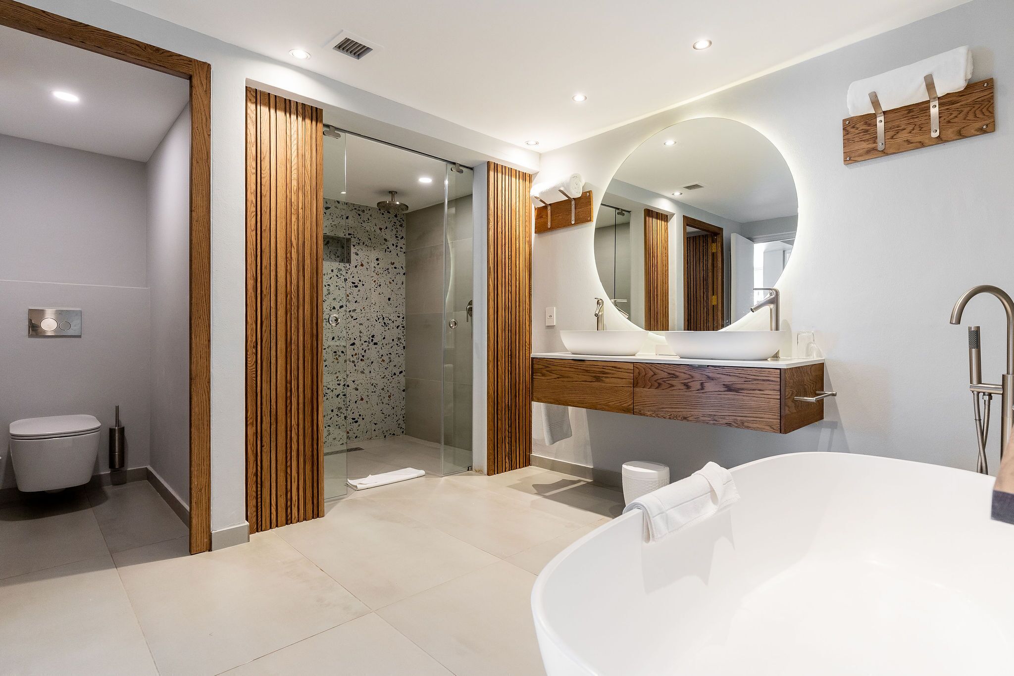 A modern bathroom with a freestanding bathtub, a wooden vanity, and a glass shower enclosure.