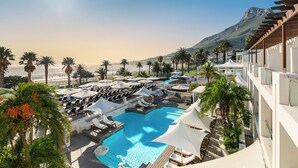 A resort with a pool, lounge chairs, and palm trees. - The Bay Hotel (Cape Town)