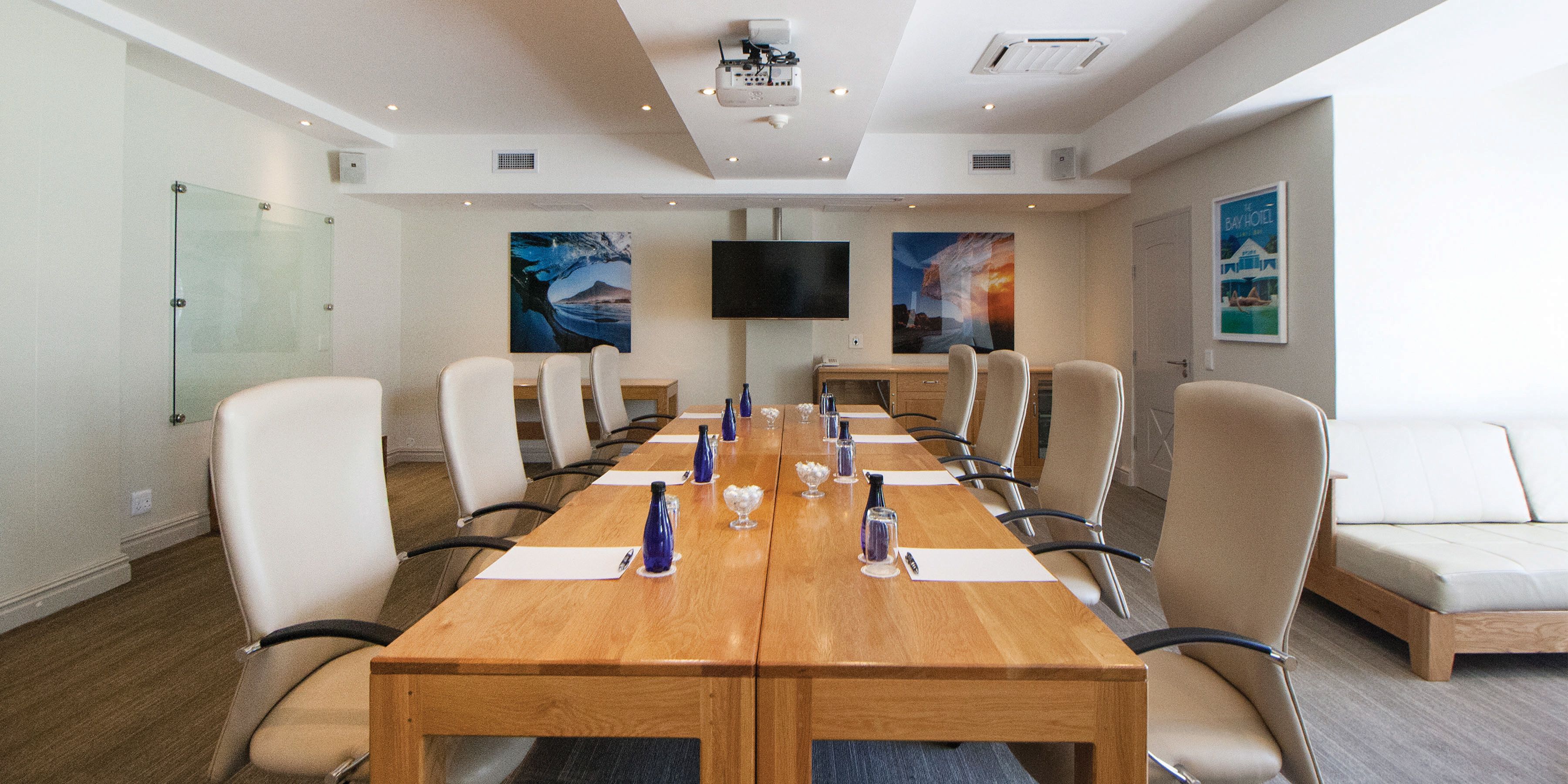 A conference room with a long table, multiple chairs, a TV, and artwork on the walls.
