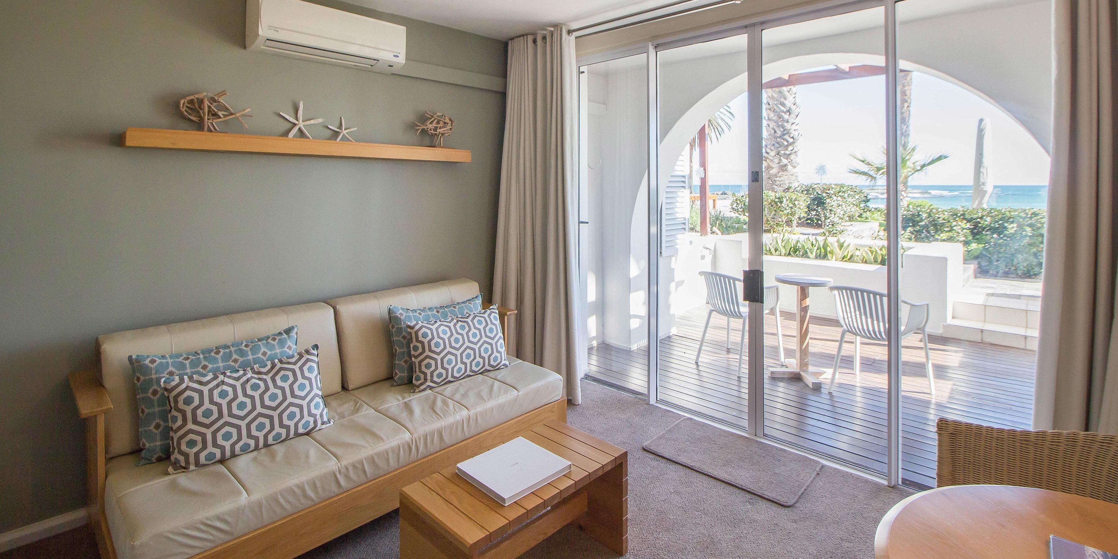 A modern living room with a sofa, coffee table, and a view of the outdoor patio area.