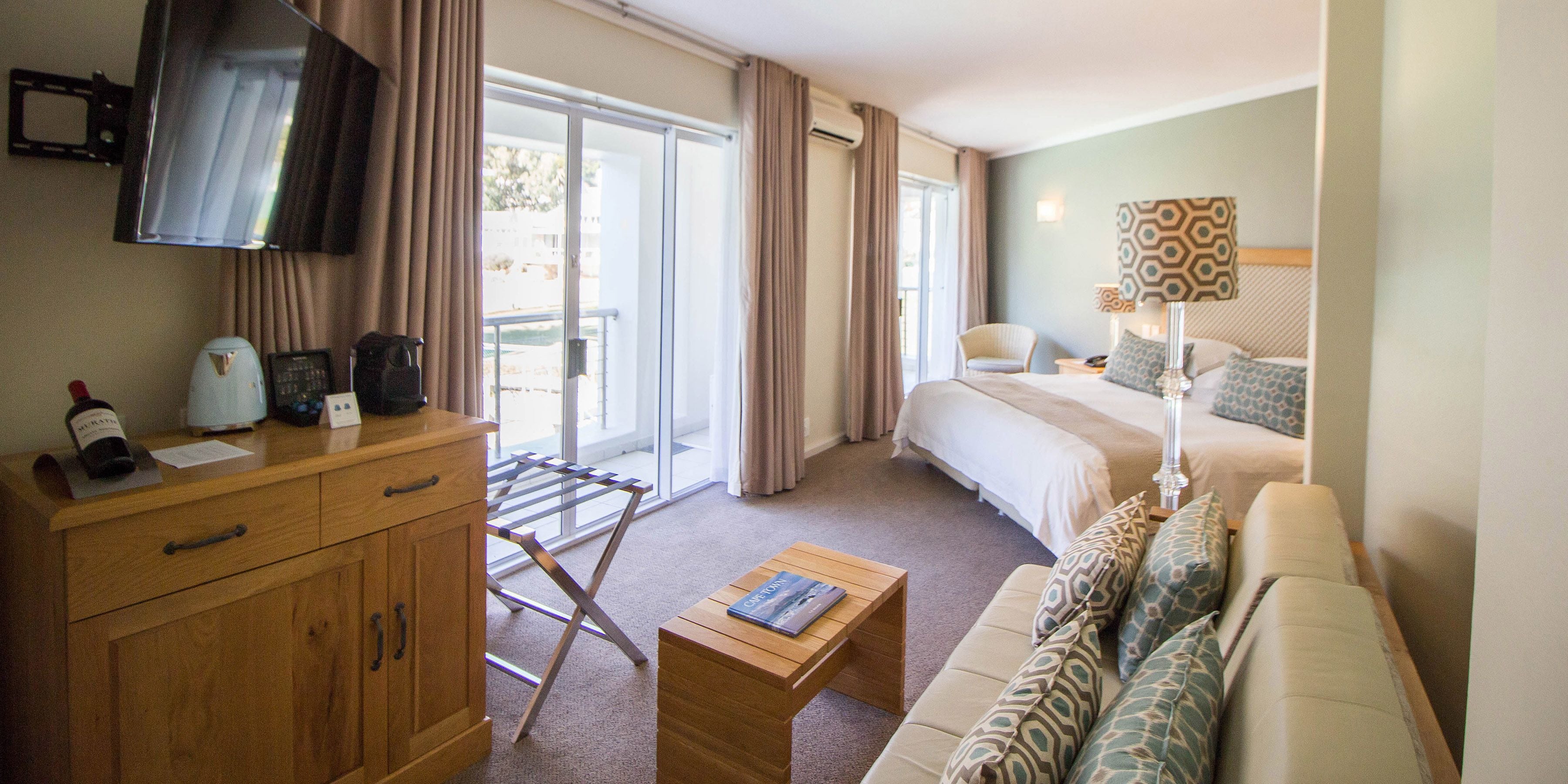 A hotel room with a bed, a sofa, a wooden cabinet, a television, and a window with curtains.