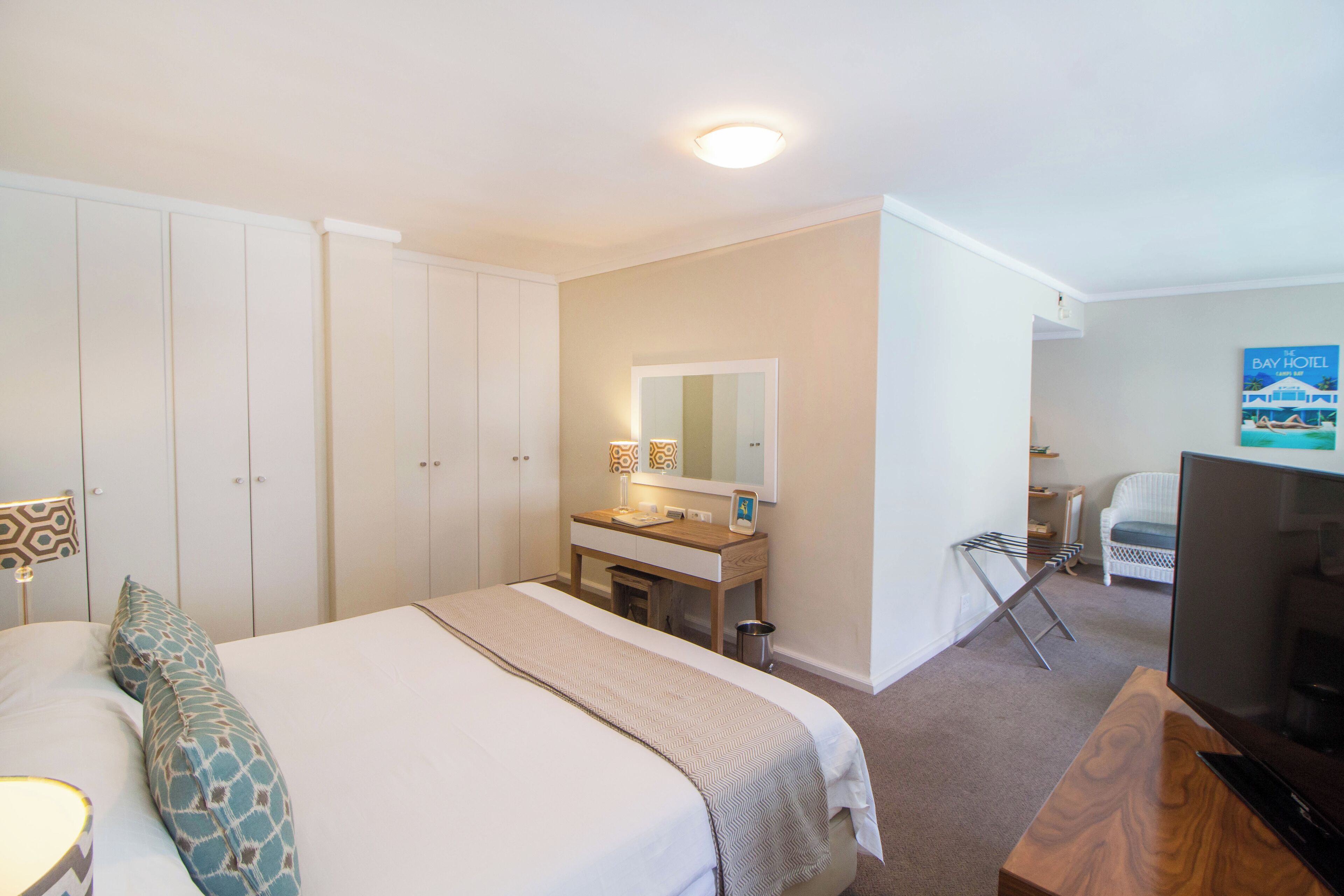 A hotel room with a bed, a desk, a television, and a bathroom.