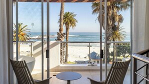 A balcony with a view of the beach, palm trees, and the ocean. - The Bay Hotel (Cape Town)