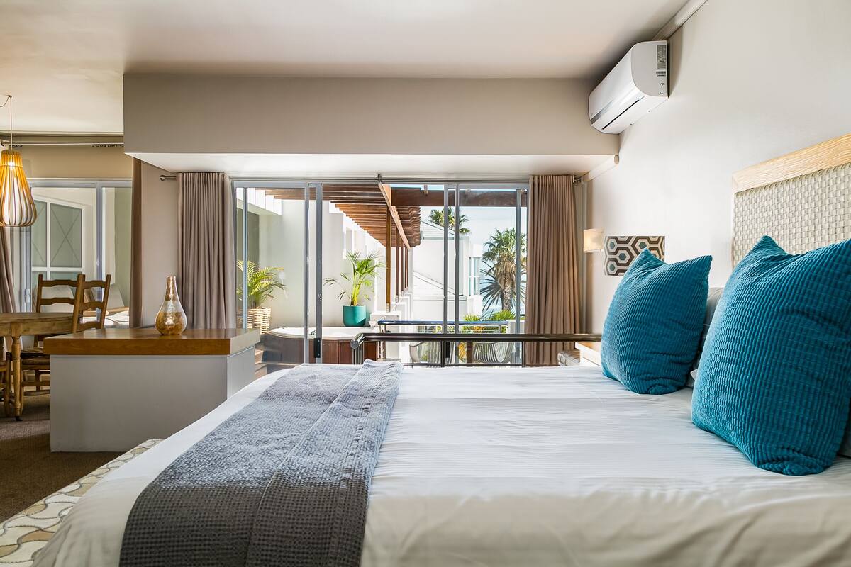 Ein Hotelzimmer mit Bett, Schreibtisch und Balkon mit Pflanzen.