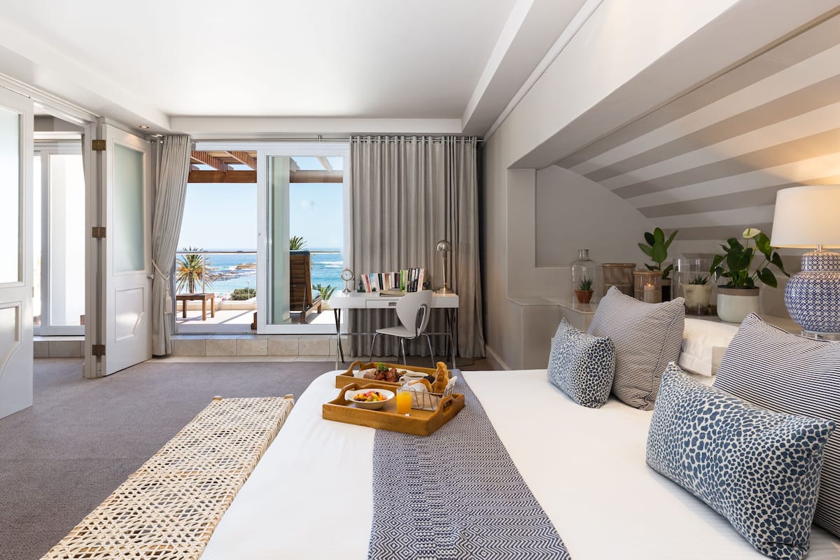 Ein Hotelzimmer mit Bett, Frühstückswagen, Schreibtisch und Meerblick.