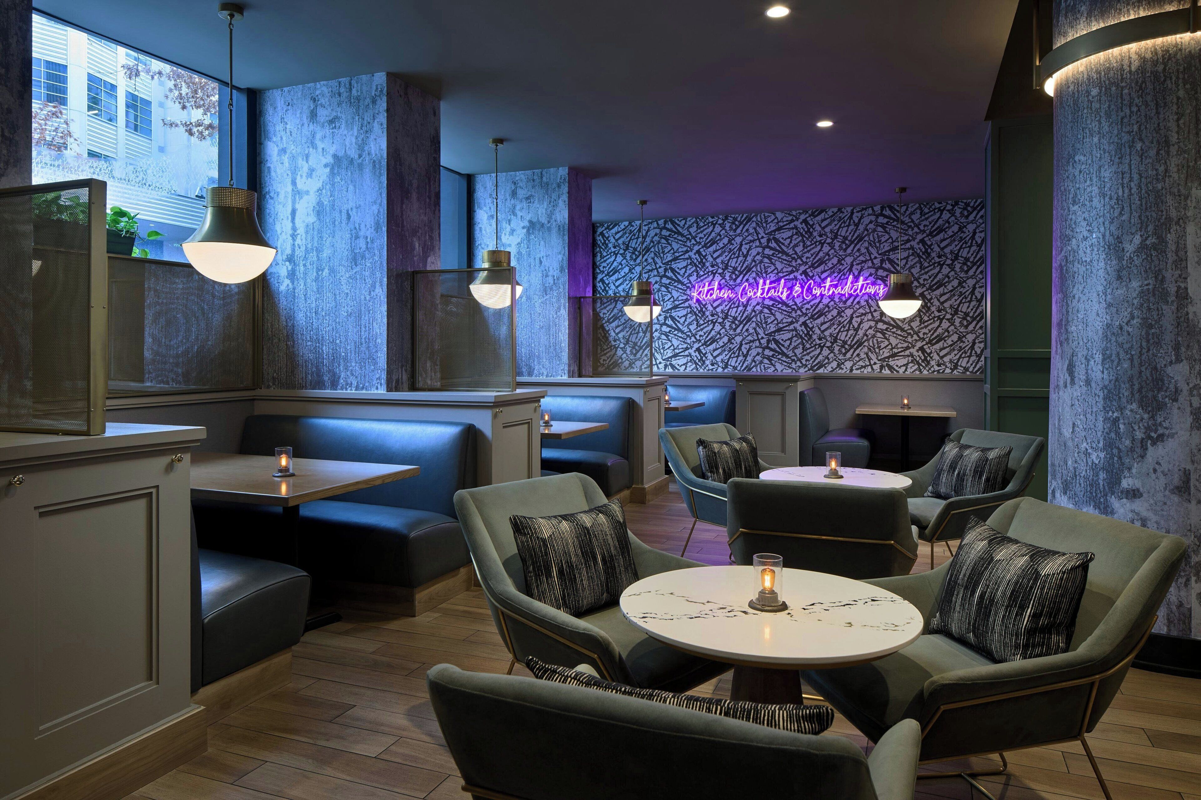 A restaurant with booths and tables, neon sign, and patterned wall.