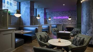 A restaurant with booths and tables, neon sign, and patterned wall.