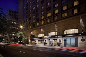 Un hotel Marriott con fachada moderna, ventanas amplias y una destacada bandera estadounidense.