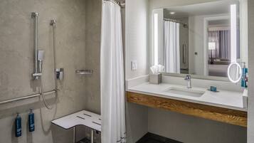 Un baño moderno con ducha, tocador con espejo y encimera de madera.