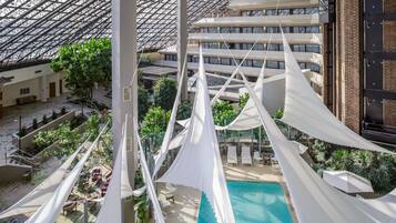 A high-rise hotel with a rooftop pool, indoor garden, and multiple balconies.