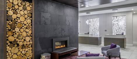 A modern interior with a fireplace, seating, and a reception desk.