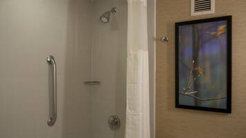 A shower with a grab bar, a towel rack, and a framed picture on the wall.