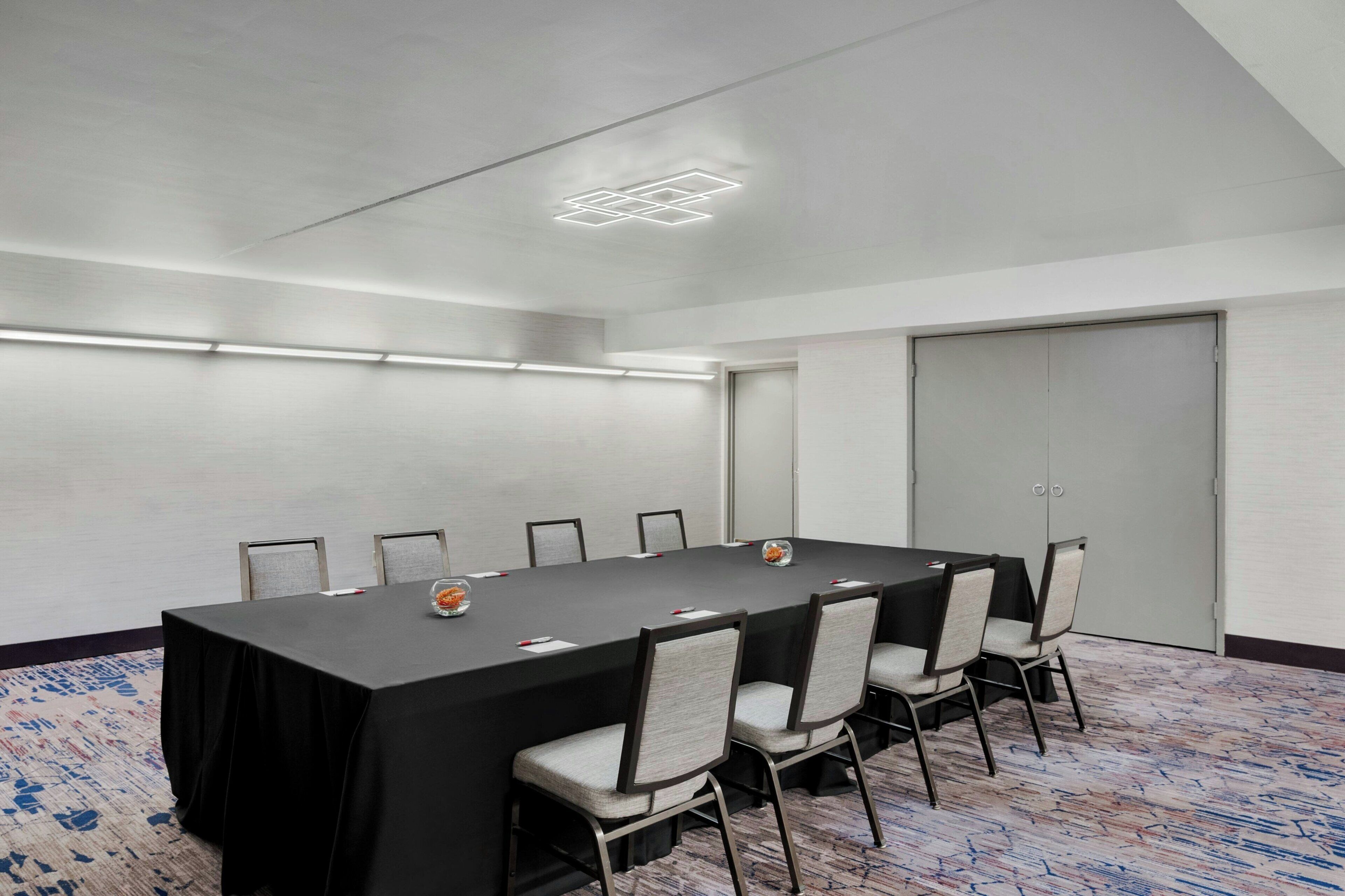 Une salle de conférence avec une longue table, six chaises et un sol recouvert de moquette.