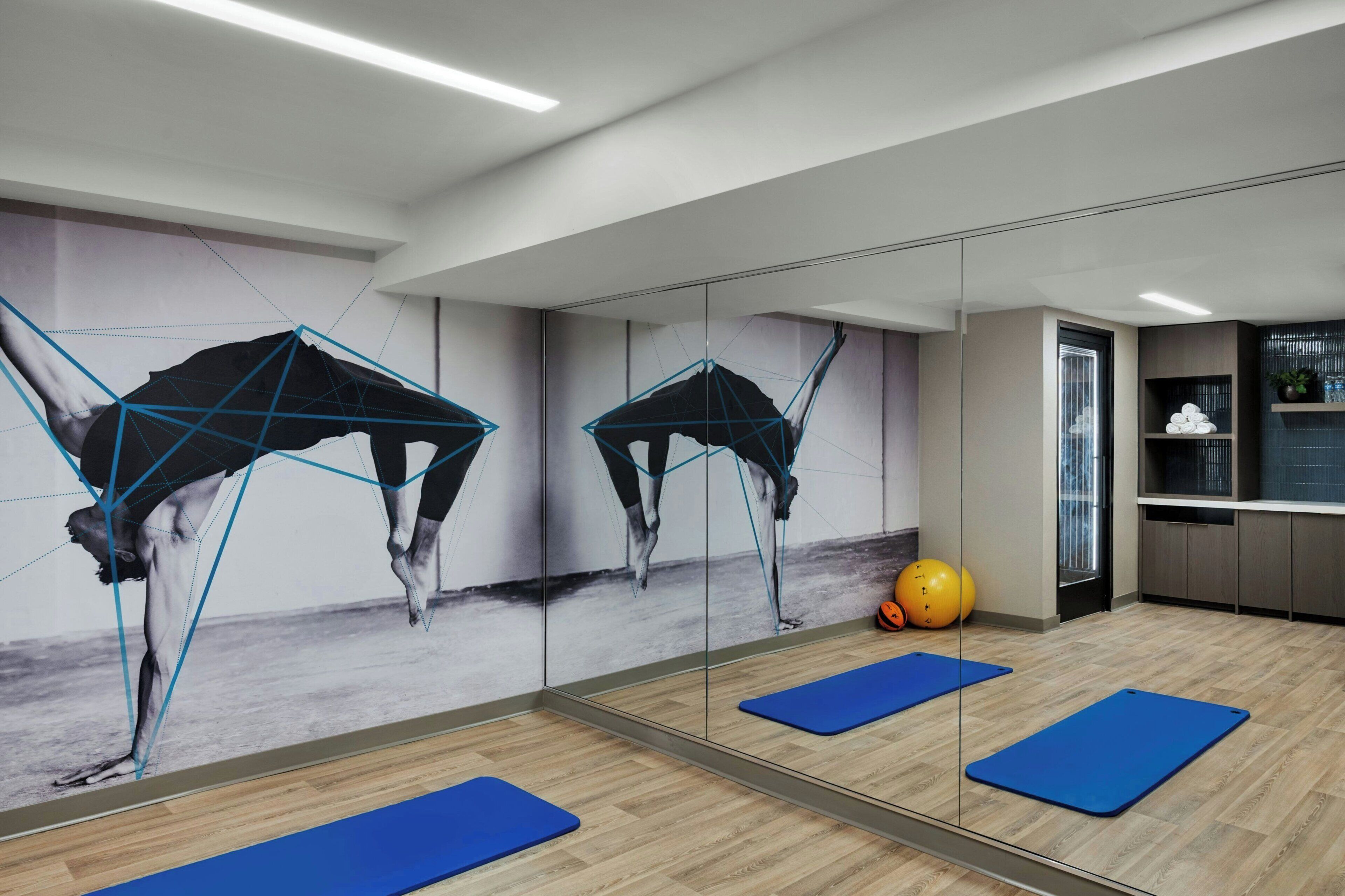 Una palestra con tappetini da ginnastica, uno specchio e una palla yoga.
