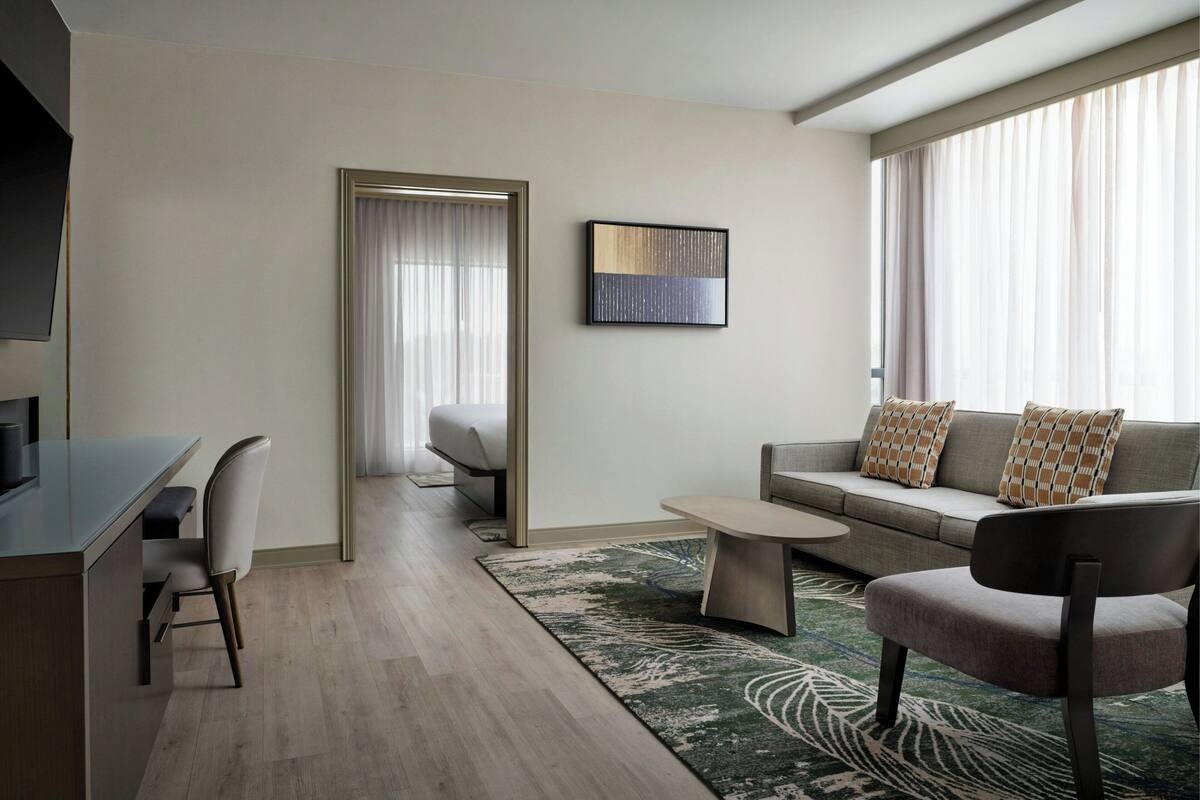 A modern living room with a sofa, a coffee table, a chair, and a TV.