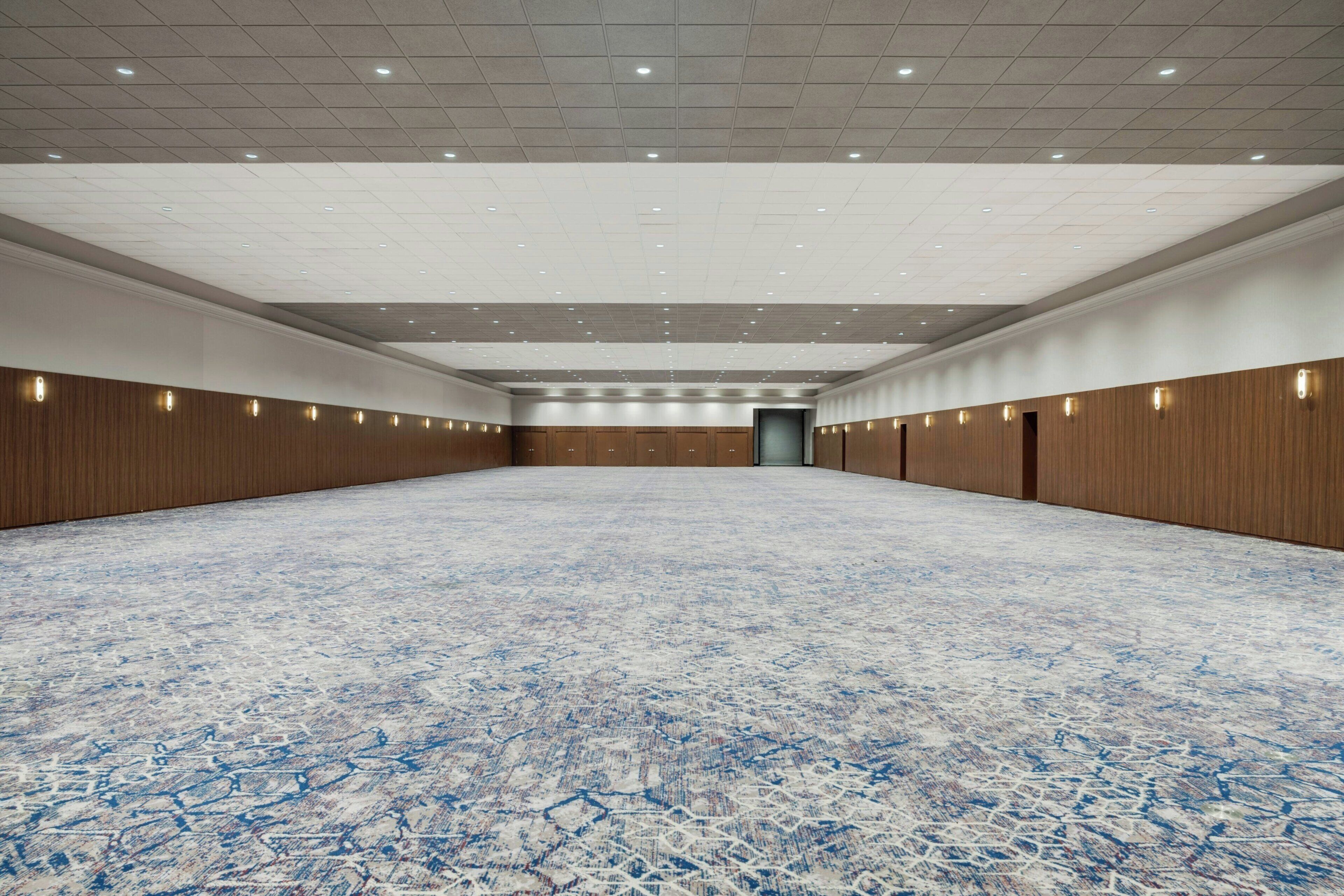 A large, empty conference room with a patterned carpet, wooden panel walls, and recessed lighting.
