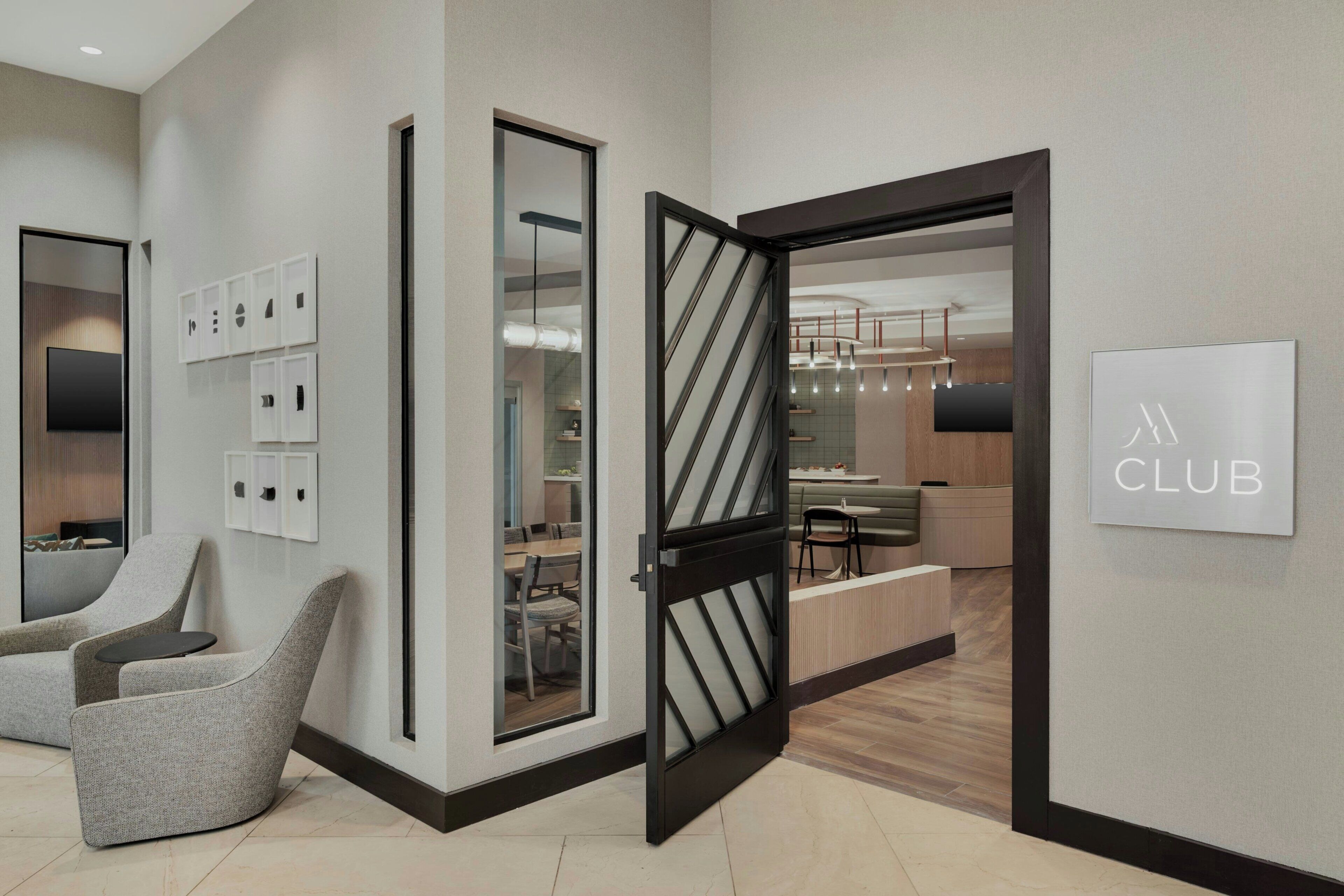 A modern interior with a reception desk, seating area, and a dining space.