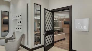 A modern interior with a reception desk, seating area, and a dining space.
