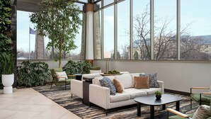 A modern living room with a large window, a sofa set, a coffee table, and a potted plant. - Marriott Indianapolis East (Indianapolis)