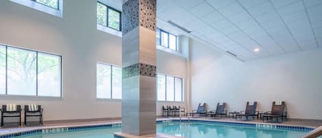 An indoor swimming pool with clear water, a tiled edge, and a central pillar.