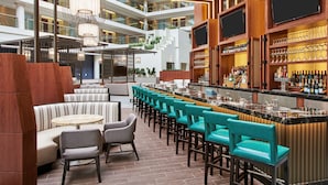 A modern hotel lobby with a bar area, seating arrangements, and a high ceiling with lighting fixtures. - Embassy Suites by Hilton Washington DC Georgetown (Washington)