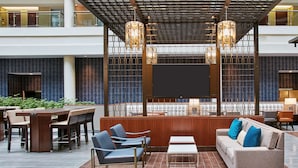 A modern lobby with a large seating area, a flat-screen TV, and decorative lighting. - Embassy Suites by Hilton Washington DC Georgetown (Washington)