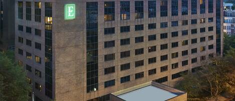 A multi-story building with a prominent 'Embassy Suites' sign on the ground floor, featuring a covered entrance and a parking area.