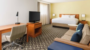A hotel room with a bed, a desk with a television, a chair, and a sofa. - Residence Inn by Marriott Hartford/Windsor (Windsor)