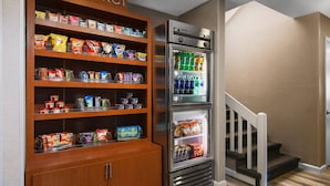 A kitchenette with a wooden shelf unit labeled 'market' stocked with snacks and a refrigerator with beverages. - Residence Inn by Marriott Hartford/Windsor (Windsor)