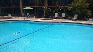 A clear blue pool with lane markers, a diving board, and a pool rule sign.