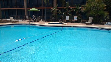 Una piscina al aire libre, sillones reclinables de piscina