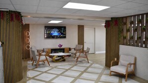 Eine moderne Hotelhalle mit einer zentralen Sitzgruppe, einem Fernseher und Zierpflanzen.